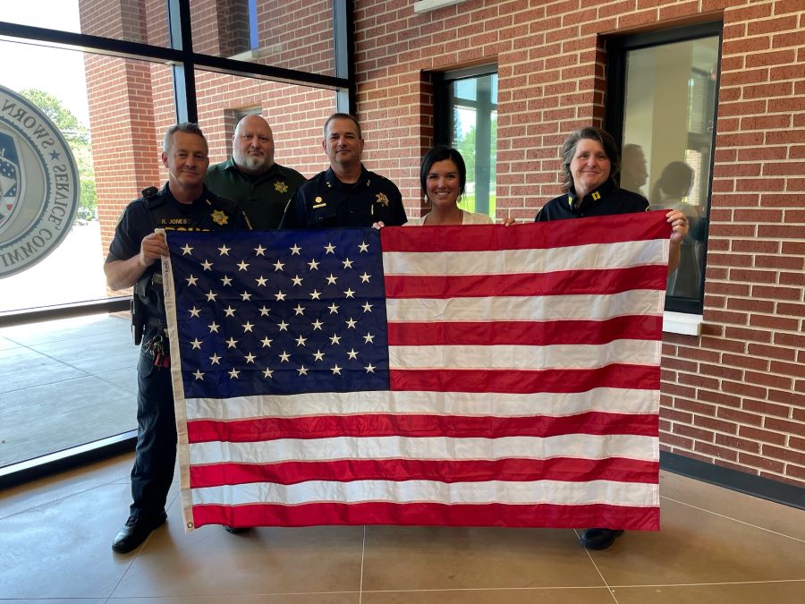 A WoodmenLife Representative stands with four police officers. Together, they are holding an American flag.