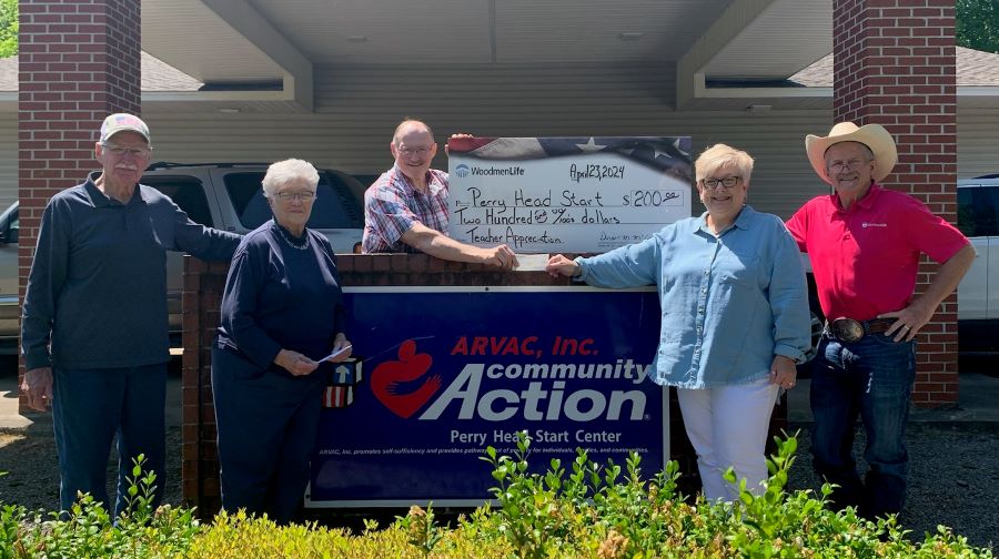 Five people stand outside of a building. They are displaying an oversized check for $200 made out to Perry Head Start. A sign on the building says "ARVAC, Inc., Community Action, Perry Head Start Center."