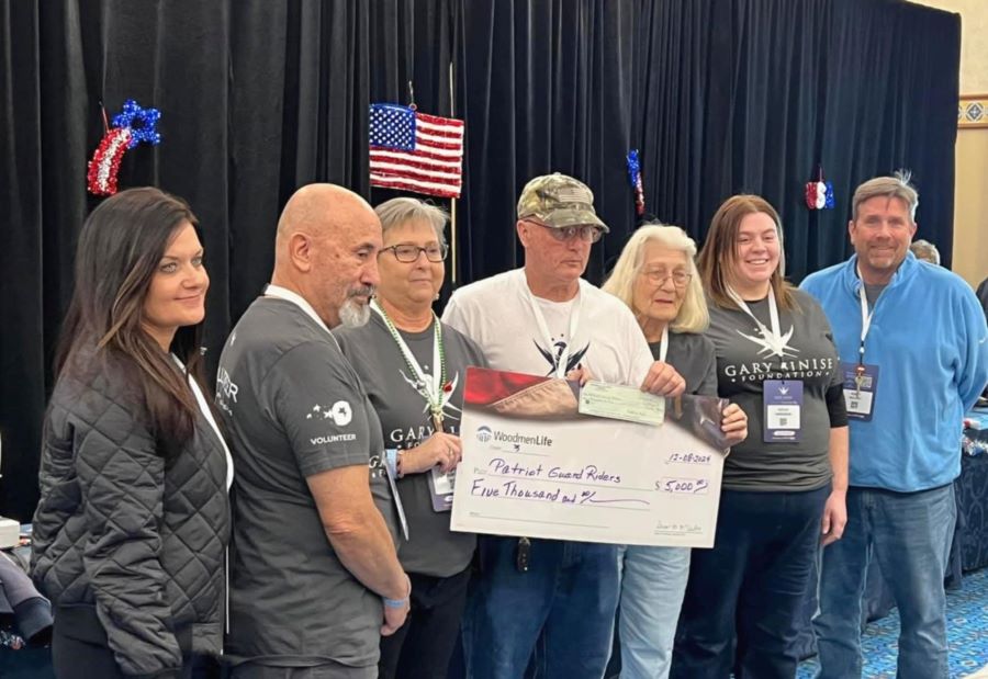 Seven people stand together around an oversized check. The WoodmenLife-branded check is made out to Patriot Guard Riders in the amount of $5,000.