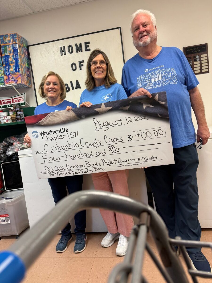 Photo shows three people standing together holding an oversized check. The check is made out to Columbia County Cares in the amount of $400.