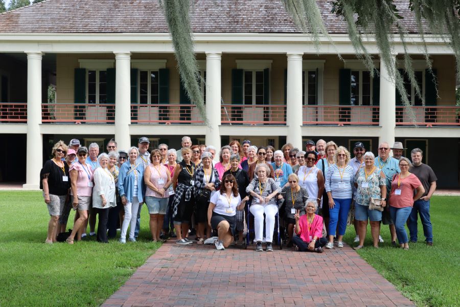 A group of about 50 people pose for a picture outside of the historic Destrehan Plantation.