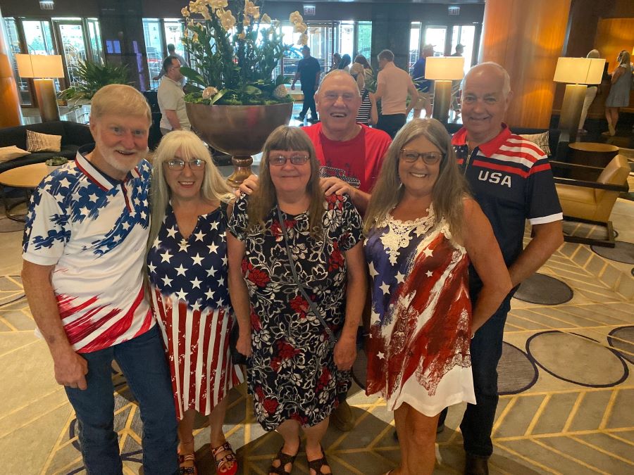 Six people stand together for a photo. They are all wearing red, white and blue clothing.