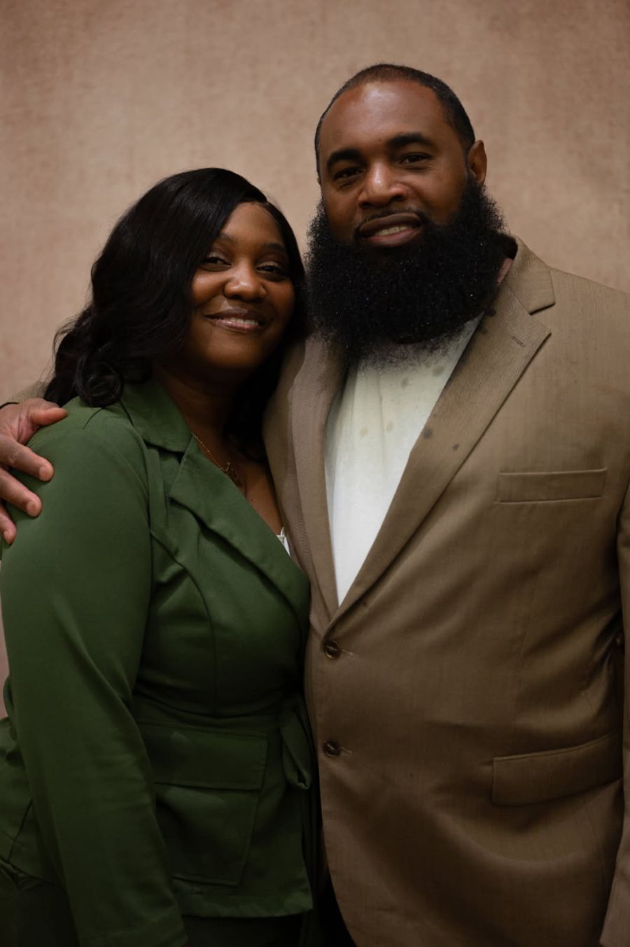 Photo shows a man and a woman posing for the camera. His arm is around her shoulder.