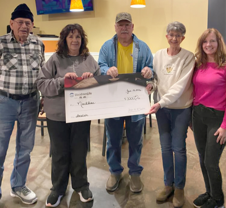 Five people stand together in the photo. They are holding an oversized check that's made out to Need Line in the amount of $1,000.