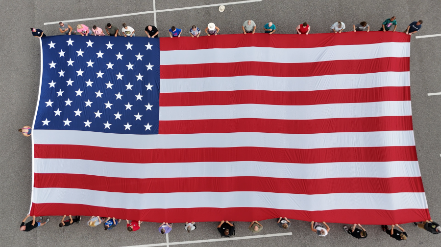 A 30-foot-by-60-foot is seen from above. People stand around the flag, holding it.