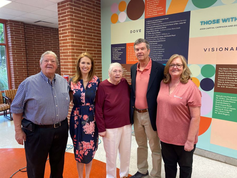 Five people stand together in front of a colorful wall at the Regional Rehab Center.