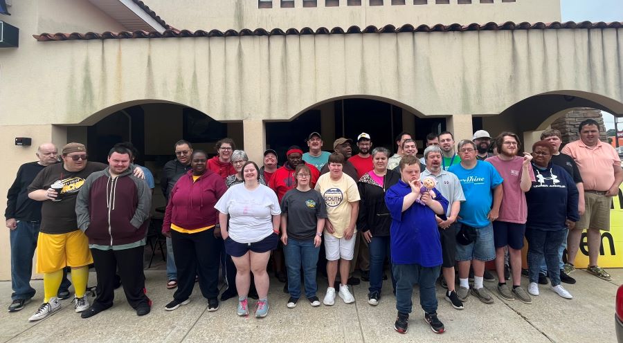 A group of about 30 people stand outside a building. These are students at New Haven Center for Special Needs Adults.