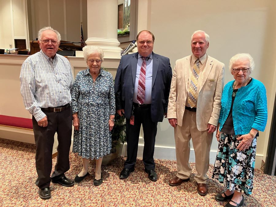 A group of five people stand together posing for the photo.