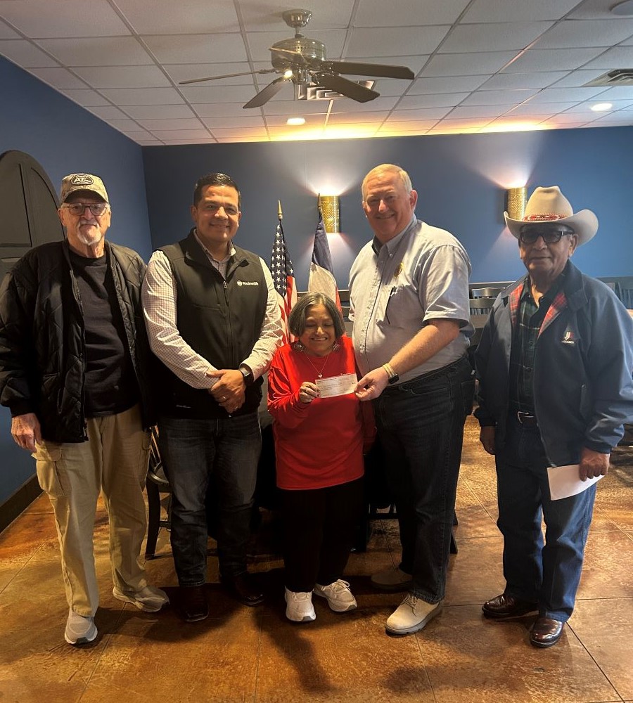 Five people stand together. Two people in the middle are holding a check, which is a donation to Operation Facelift 2025.