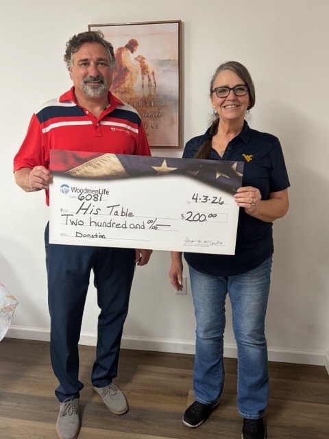 A man and a woman stand together for the photo. They are holding an oversized check made out to "His Table" in the amount of $200.