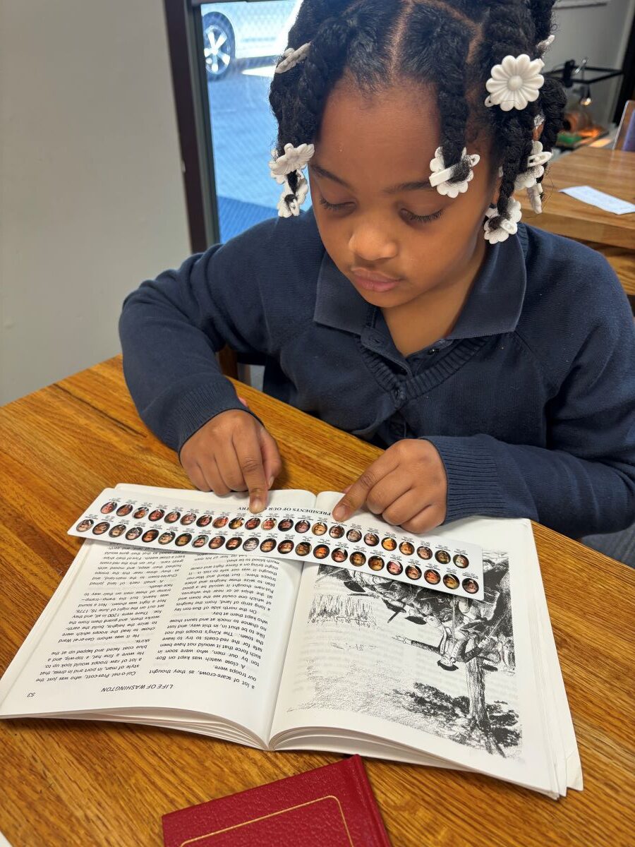 A second-grade student looks at her ruler, which has the faces of all the U.S. presidents on it.