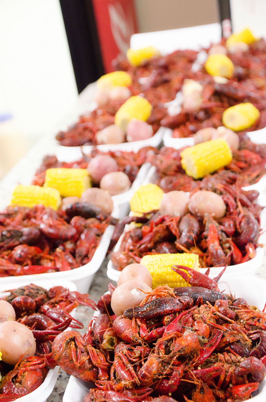 Photo shows a long table full of plates with crawfish, potatoes, and corn-on-the-cob.