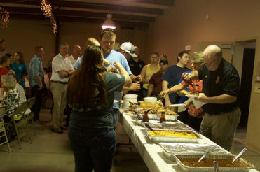 Dozens of people wait in line to be served a barbecue buffet.