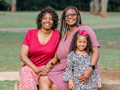 WoodmenLife member Desarea Thompson is seated and posing for a picture with her mother, Vilena Thompson, to the left and her goddaughter, Rose, to the right.