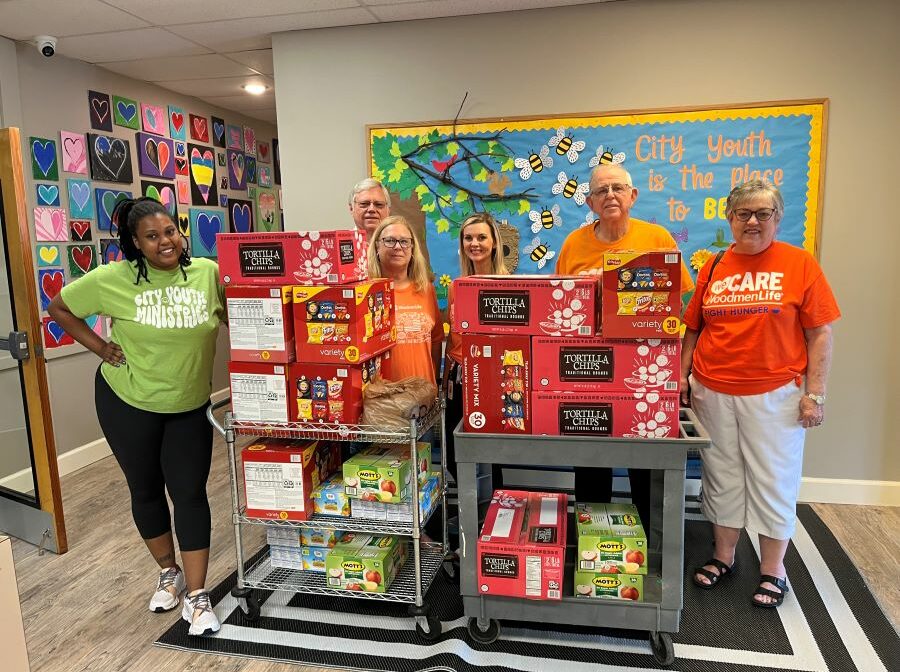 Six people stand around two carts full of donated food.