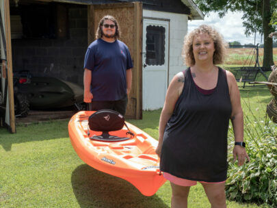 WoodmenLife member Angela Hunt and her 16-year-old son, Price, each carry one end of a kayak. For them, kayaking is a great way of staying active as a family.