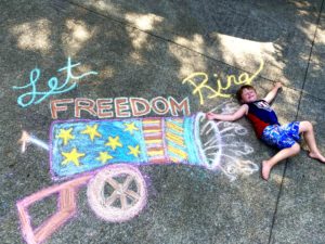 Patriotic chalk art of a boy and a cannon and a message of Let Freedom Ring