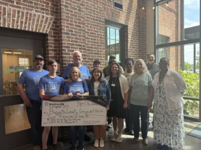 Photo shows a group of 12 people standing together with an oversized check. The check is made out to Augusta Locally Grown in the amount of $2,000.