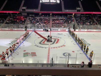This photo is taken from a high point of view, looking down onto an ice rink. The two hockey teams are lined up and facing each other.
