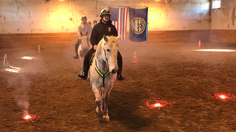 Four Omaha Police Department Mounted Patrol Unit Officers ride their horses in the training stable.
