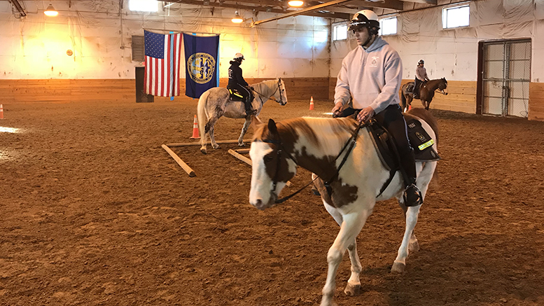 Three officers in the Omaha Police Department Mounted Patrol Unit ride each of their horses around the training facility.