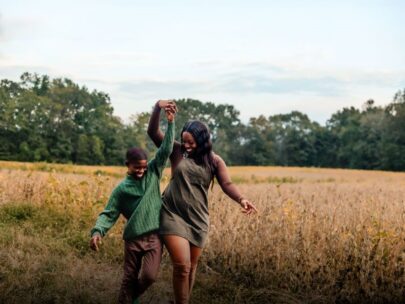 WoodmenLife member Iesha Kelley and her 12-year-old son pose for a photo. They are outdoors, with a field of native grass and trees behind them. They are holding hands as they walk.