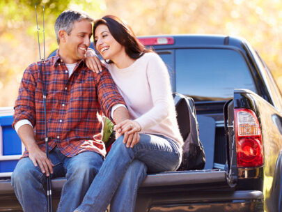 Couple sitting close together on a truck tailgate