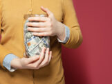 Woman holding jar of paper money