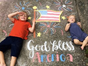 Patriotic chalk art with two children and the message God Bless America