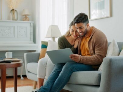 Stock image. A man and a woman are sitting on a couch and looking at a laptop screen.